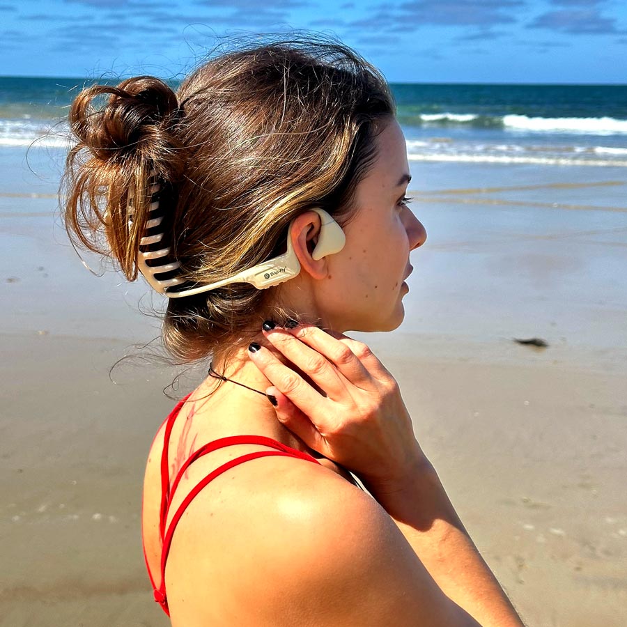 A woman wearing drip-fly oz5 beige headphones for absolute comfort