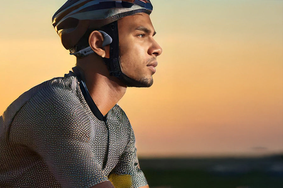 A cyclist wearing drip-fly oz5 open move headphones while riding on a cycle